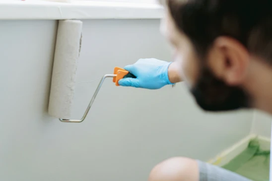 Intérieur professionnel avec peintre appliquant de la peinture blanche sur un mur à l'aide d'un rouleau