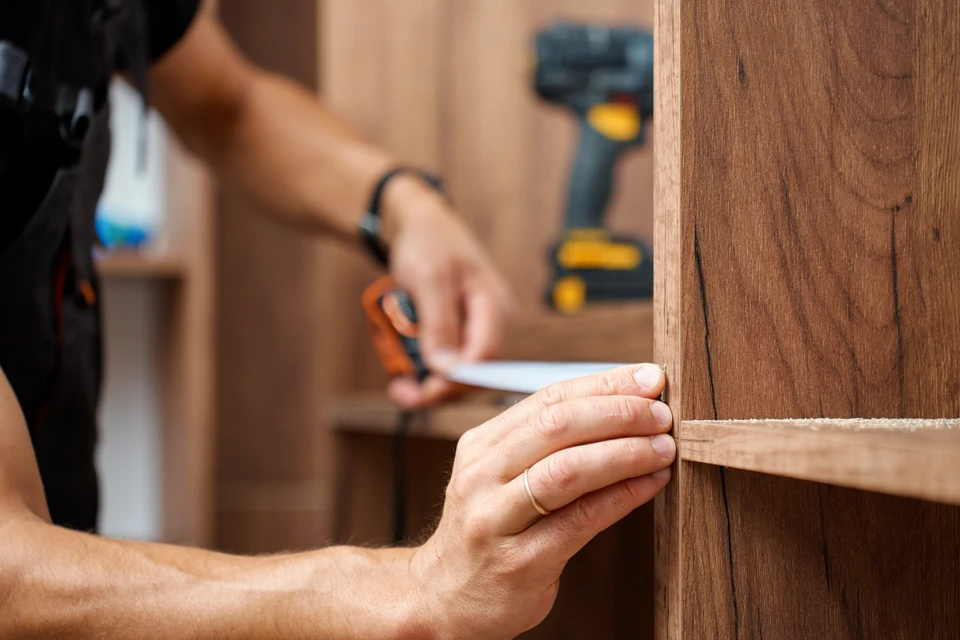 Intérieur en cours de rénovation, artisan carreleur installant du carrelage imitation bois sur chape béton